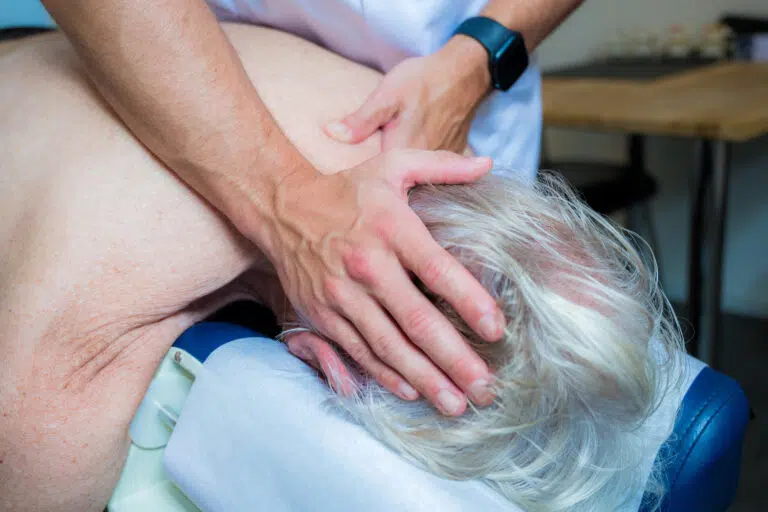 Chiropractor behandelt oudere man met hoofdpijn